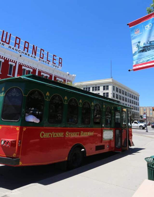 Red and green trolley passing through historic streets during a Cheyenne Trolley Tour in Laramie County, Wyoming.